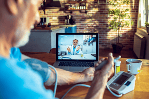 Older man with white hair checking his blood pressure and on a Telehealth appointment 