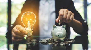 Business owner holding light bulb and putting money into piggy bank