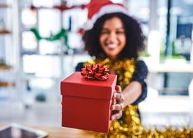 Smiling employee holding out holiday corporate gift