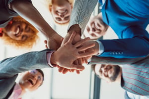 Smiling employees putting hands together in a circle