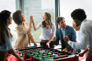 Group of healthy employees playing foosball together in the office