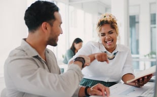 Enthusiastic employees bumping fists at office desk