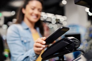 Woman using her mobile phone to pay at a store