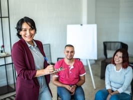 Smiling researcher collecting information from two seated study participants