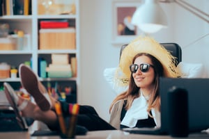 Employee in sunglasses and sun hat relaxing at office desk