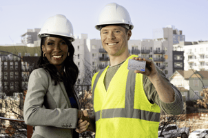 Smiling foreman with construction worker showing off Visa Rewards card