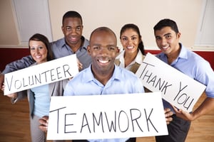 Smiling volunteers holding up signs that say 