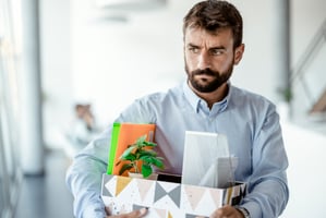 Frustrated employee revenge quitting with box of packed office supplies