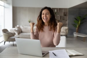 Employee celebrating at her desk after receiving digital gift card