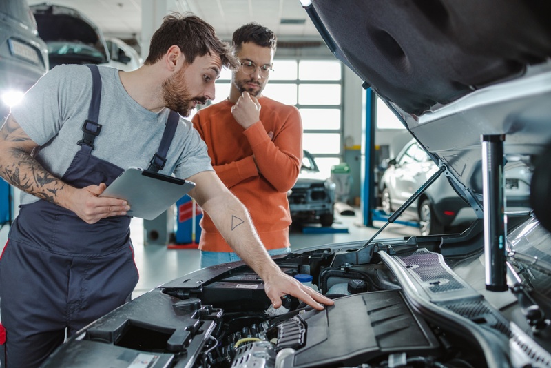 Automotive mechanic showing customer car engine