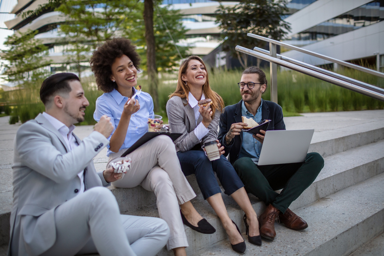Group of happy, healthy employees eating lunch outside together